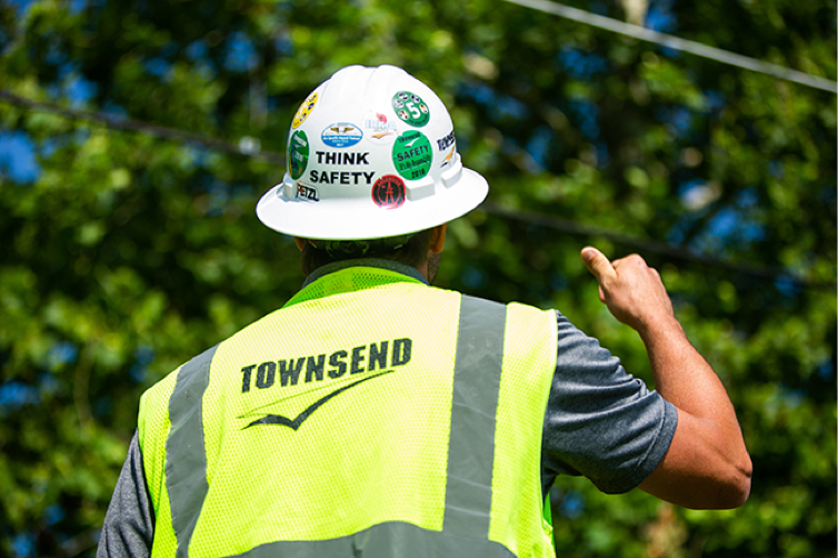 Townsend employee in high visibility clothing, wearing a hard at with stickers that read think safety.
