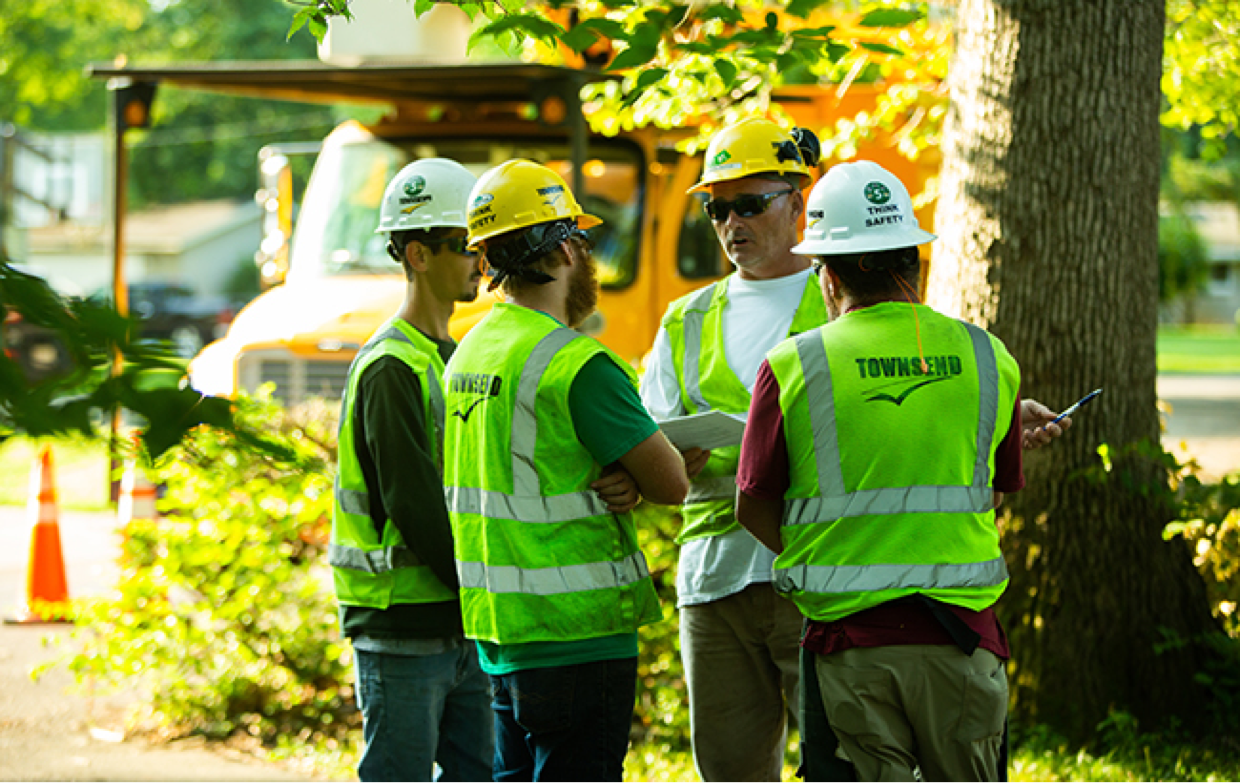 Group of 4 Townsend employees wearing high visibility workwear and having a group discussion